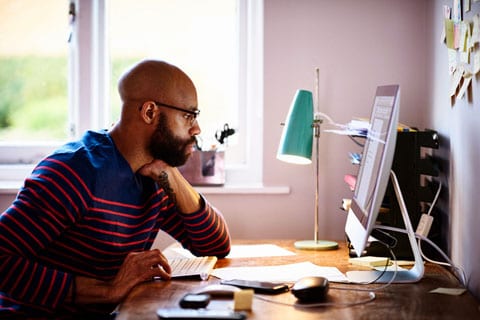 Man sitting at desk and reading a computer screen.